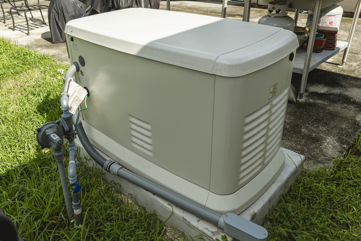 A Home Standby Generator installed at the backyard of a house. An air-cooled natural gas or liquid propane generator for residential use.